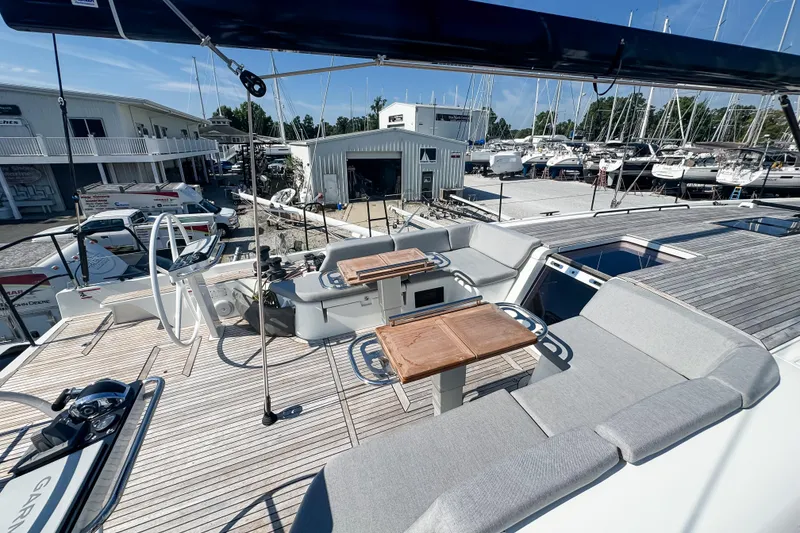 Slide: The Image of 2024 Beneteau First 53 yacht deck with seating and dual steering wheels in marina setting. - 11