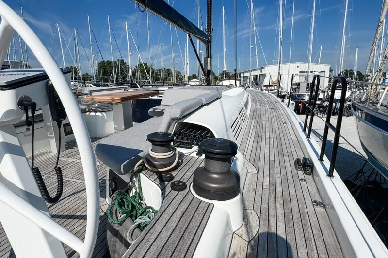 Slide: The Image of 2024 Beneteau First 53 sailboat deck with winches and steering wheel, docked in marina. - 7