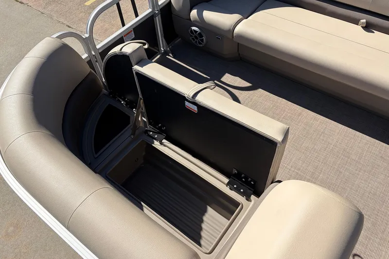 Slide: The Image of 2024 Sun Tracker Party Barge 18 DLX interior with open storage compartment and beige seating. - 17