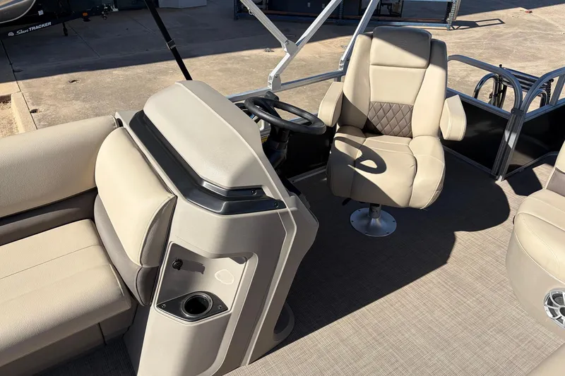 Slide: The Image of 2024 Sun Tracker Party Barge 18 DLX interior with beige seating and steering console. - 25