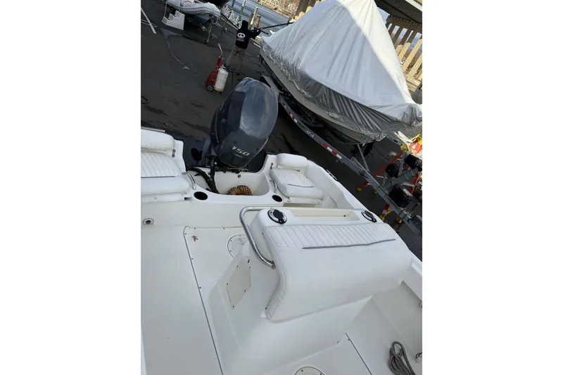 Slide: The Image of 2004 Boston Whaler 190 Nantucket boat with outboard motor, docked and covered nearby. - 10