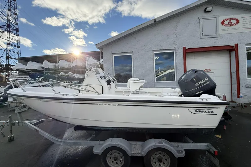 Slide: The Image of 2004 Boston Whaler 190 Nantucket boat on trailer, parked outside a marine workshop. - 3