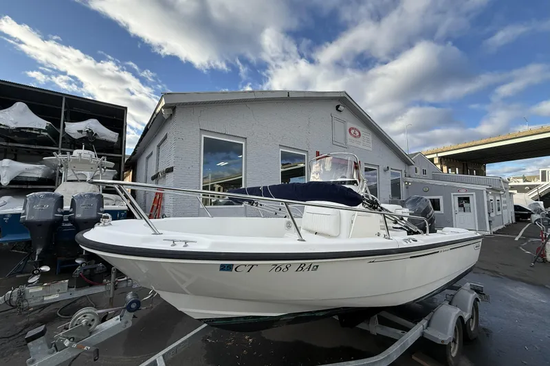 Slide: The Image of 2004 Boston Whaler 190 Nantucket boat on trailer, parked outside a marine facility. - 4