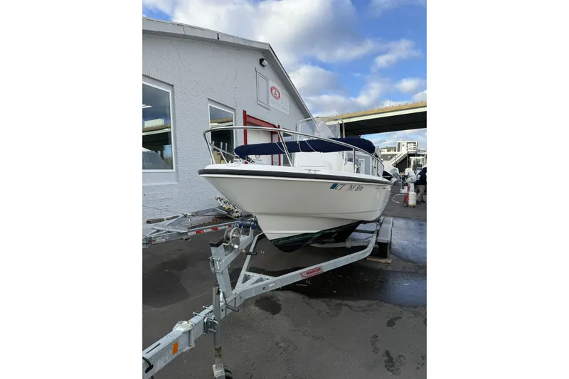 Slide: The Image of 2004 Boston Whaler 190 Nantucket boat on trailer, parked outside a building. - 6