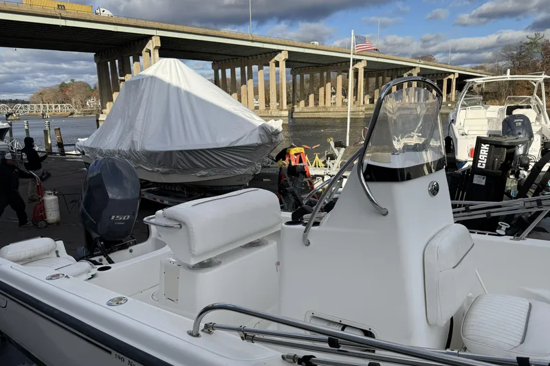 Slide: The Image of 2004 Boston Whaler 190 Nantucket boat docked near a bridge, with covered vessel nearby. - 9