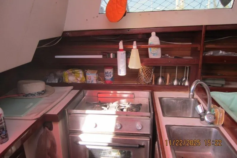 Slide: The Image of Compact kitchen in a 1986 Catalina 30 MkII sailboat with stove, sink, and storage shelves. - 32