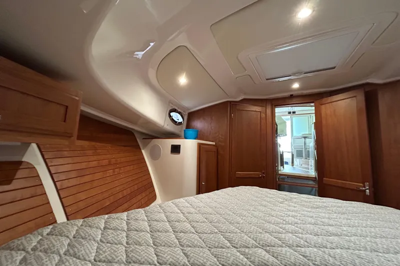 Slide: The Image of 2023 Back Cove 39O cabin interior with wood paneling and cozy bedding. - 49
