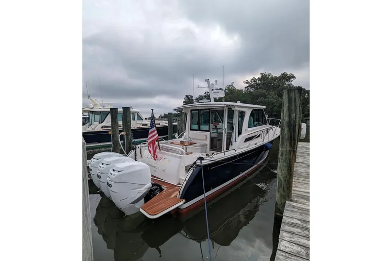 Slide: The Image of 2023 Back Cove 39O boat docked with triple outboard engines and American flag. - 61