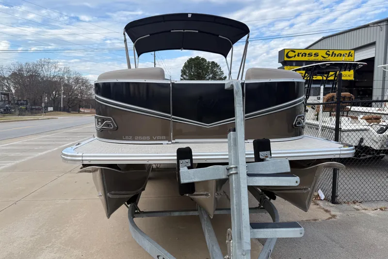 Slide: The Image of 2026 Avalon LSZ Versatile Rear Bench pontoon boat on trailer, parked outside dealership. - 2