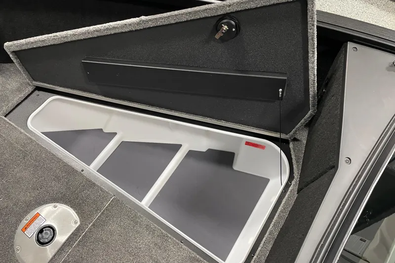 Slide: The Image of Open storage compartment in 2026 Alumacraft Competitor 175X Sport boat, featuring carpeted interior. - 9