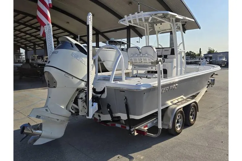 Slide: The Image of 2021 Sea Pro 248 Bay boat on trailer, featuring outboard motor and T-top, parked outdoors. - 7