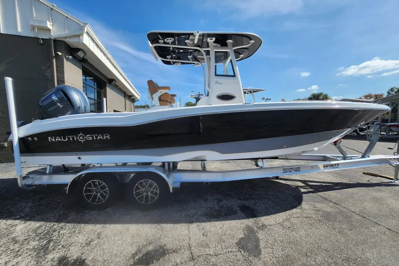 The Image of 2026 NauticStar 251 Hybrid boat on trailer, side view under clear blue sky. - 1