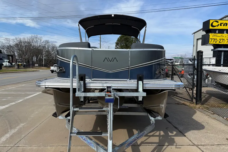 Slide: The Image of 2026 Avalon LSZ Versatile Rear Lounger pontoon boat on trailer, parked outdoors. - 2