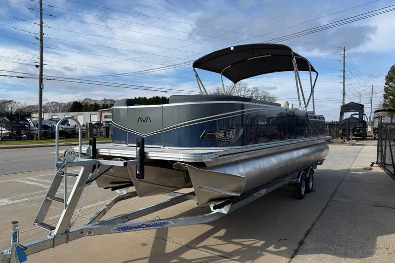 Slide: The Image of 2026 Avalon LSZ Versatile Rear Lounger pontoon boat on trailer, parked outdoors. - 3
