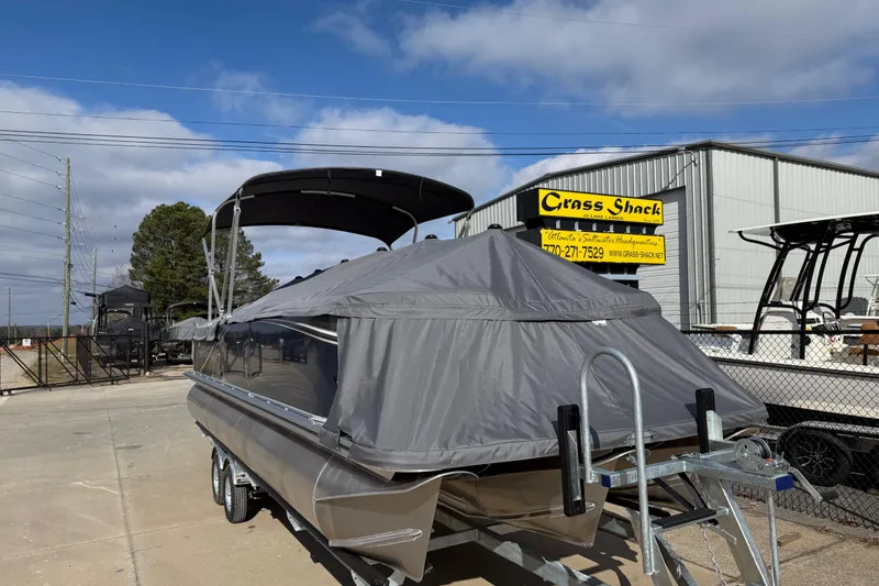 Slide: The Image of 2026 Avalon LSZ Versatile Rear Lounger boat covered, parked at Grass Shack dealership. - 5
