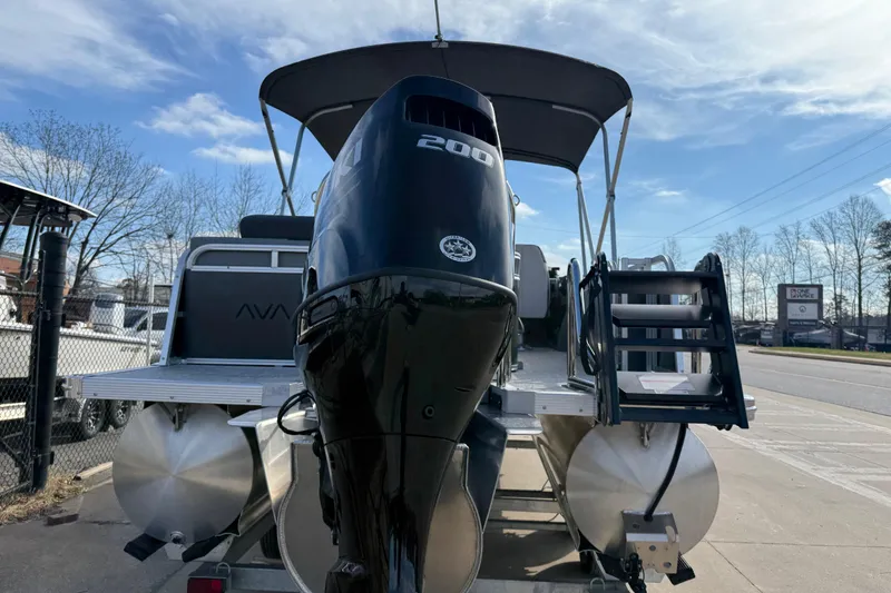 Slide: The Image of 2026 Avalon LSZ Versatile Rear Lounger boat with powerful outboard motor, docked outdoors. - 8