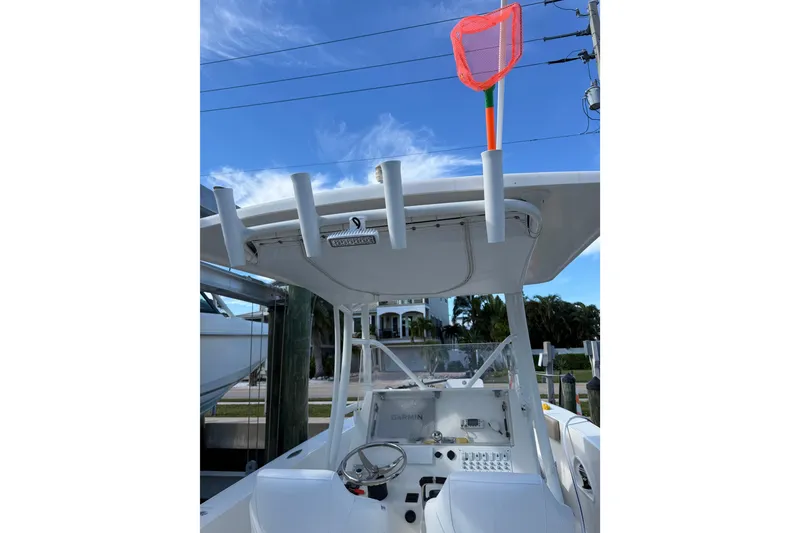 Slide: The Image of 2017 Stamas 308 Predator boat helm with rod holders and net, under clear blue sky. - 15