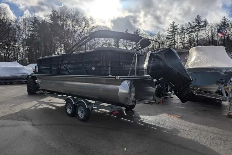 Slide: The Image of 2025 Berkshire 22CL CTS 3.0 pontoon boat on trailer, parked outdoors. - 2