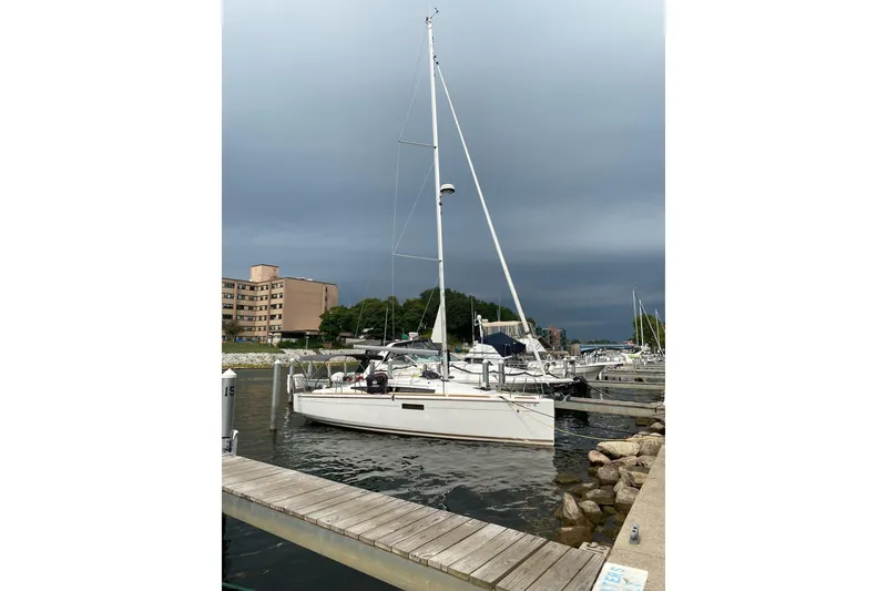 The Image of 2023 Jeanneau Sun Odyssey 349 sailboat docked at a marina under cloudy skies. - 0