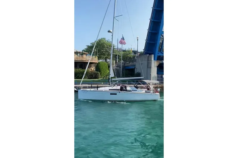 Slide: The Image of 2023 Jeanneau Sun Odyssey 349 sailing under a raised bridge on a sunny day. - 1