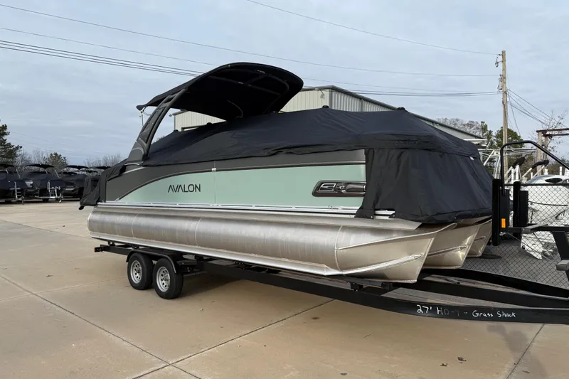 Slide: The Image of 2026 Avalon Catalina Quad Lounger Windshield pontoon boat on trailer, covered, in outdoor setting. - 44