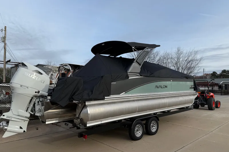 Slide: The Image of 2026 Avalon Catalina Quad Lounger Windshield boat on trailer, covered, with Suzuki outboard motor. - 45