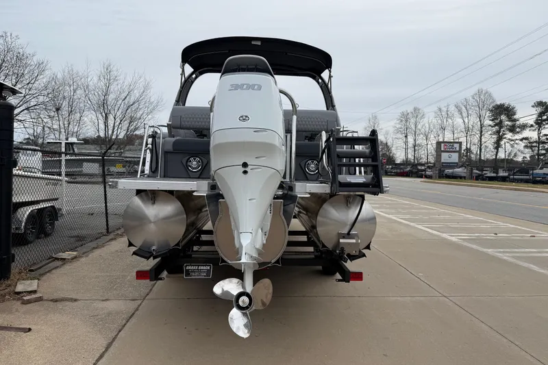 Slide: The Image of 2026 Avalon Catalina Quad Lounger Windshield boat with powerful outboard motor, parked on pavement. - 5