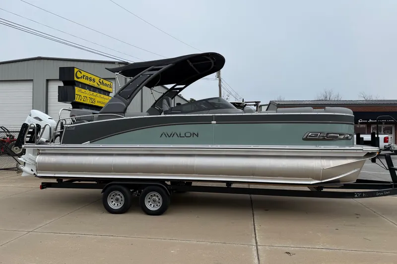 Slide: The Image of 2026 Avalon Catalina Quad Lounger Windshield pontoon boat on trailer, parked outside. - 7