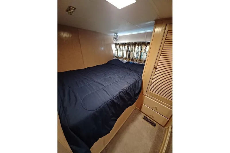 Slide: The Image of Cozy bedroom in 1996 Stardust Cruisers 1655 houseboat with blue bedding and wooden cabinetry. - 14