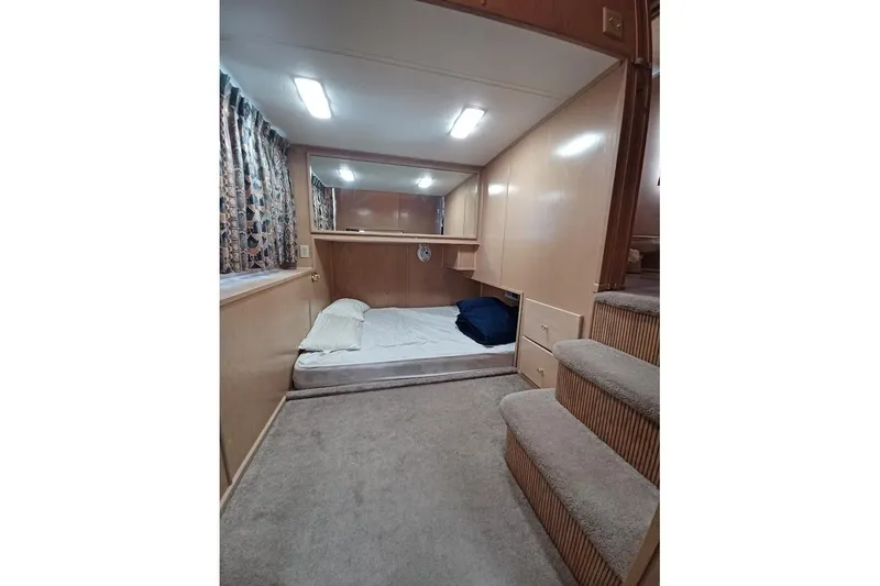 Slide: The Image of 1996 Stardust Cruisers 1655 interior bedroom with bed, carpeted stairs, and wooden cabinetry. - 17