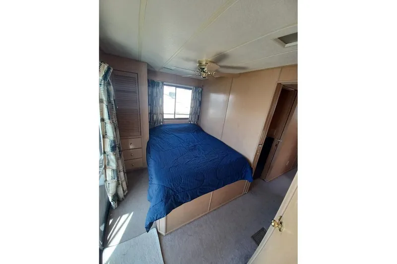 Slide: The Image of Bedroom interior of 1996 Stardust Cruisers 1655 with blue bedding and wooden accents. - 22