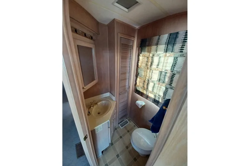 Slide: The Image of 1996 Stardust Cruisers 1655 bathroom with sink, toilet, and patterned window covering. - 26