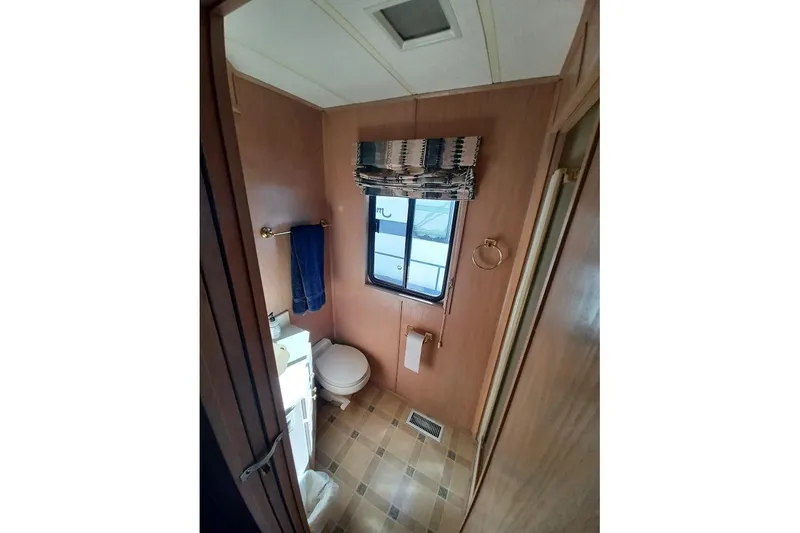 Slide: The Image of Bathroom interior of 1996 Stardust Cruisers 1655 houseboat, featuring wood paneling and window. - 28