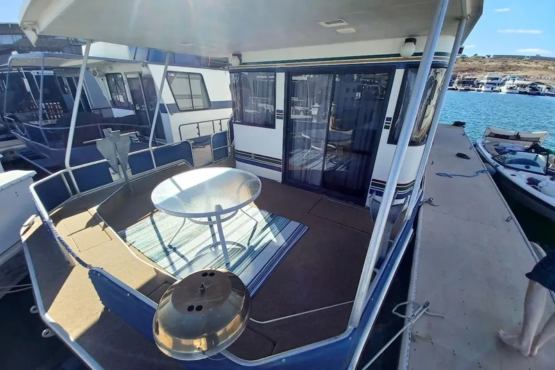 Slide: The Image of 1996 Stardust Cruisers 1655 houseboat with outdoor seating on a sunny dock. - 6