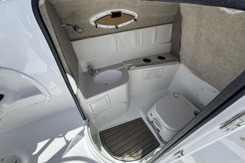 Slide: The Image of 2025 Stingray 231DC boat interior with compact bathroom, sink, and toilet. - 12