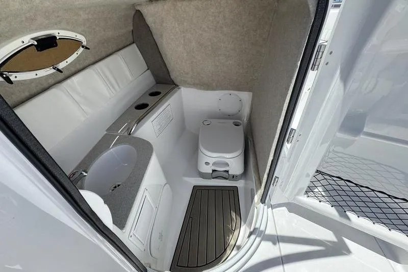 Slide: The Image of Interior of 2025 Stingray 231DC boat featuring compact bathroom with sink and toilet. - 13