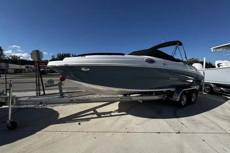 Slide: The Image of 2025 Stingray 231DC boat on trailer, parked outdoors under clear blue sky. - 2
