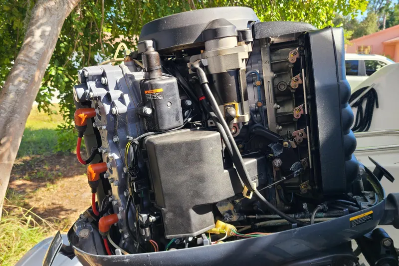 Slide: The Image of Close-up of a 2003 Aquasport 205 Osprey boat engine under a tree. - 20