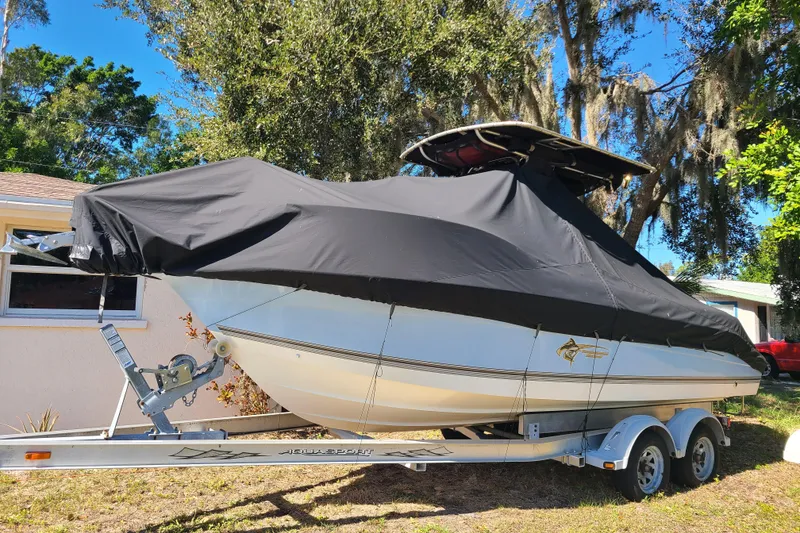 Slide: The Image of 2003 Aquasport 205 Osprey boat covered on trailer, parked outdoors. - 22