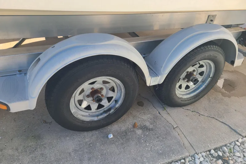 Slide: The Image of Trailer wheels of a 2003 Aquasport 205 Osprey boat on concrete surface. - 24