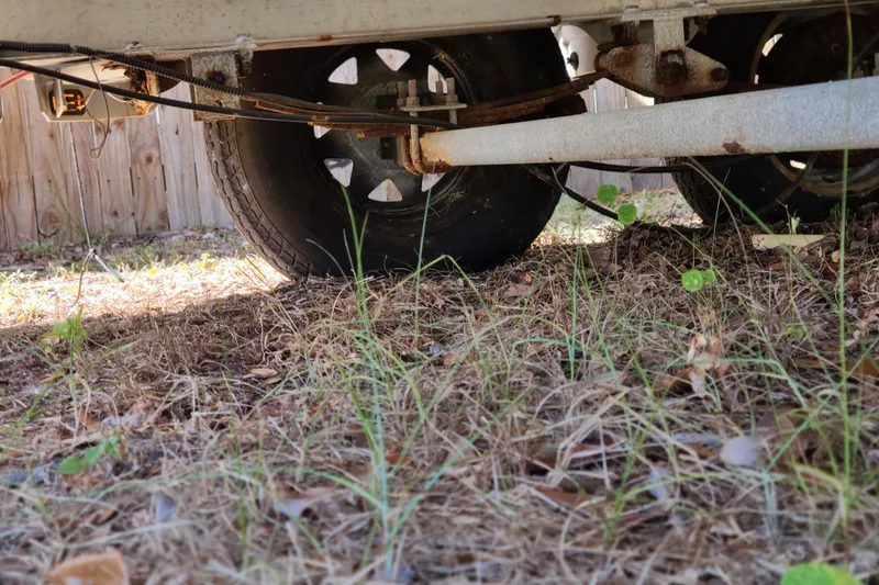 Slide: The Image of Underneath view of a 2003 Aquasport 205 Osprey trailer, showing wheels and suspension. - 25