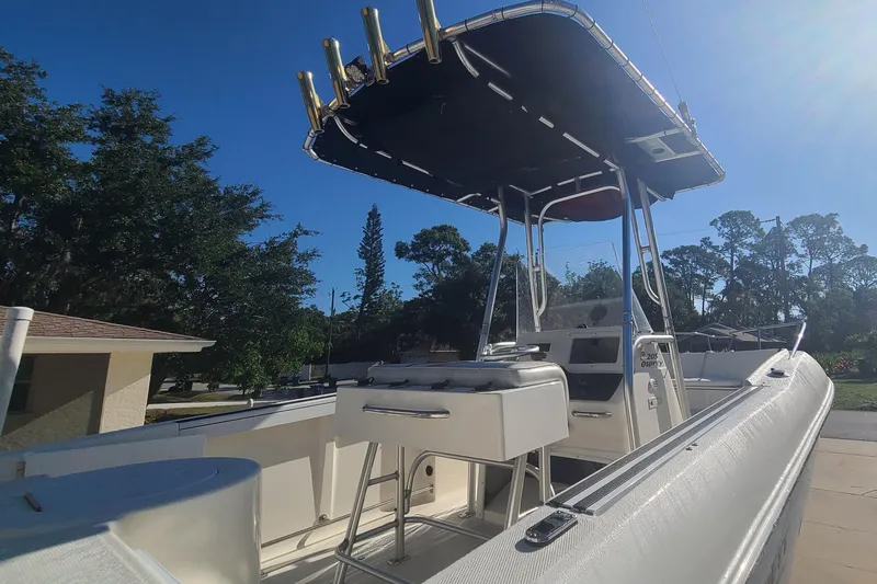 Slide: The Image of 2003 Aquasport 205 Osprey boat with T-top, parked outdoors under clear blue sky. - 4