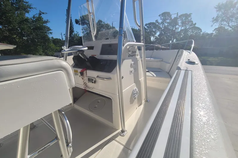 Slide: The Image of 2003 Aquasport 205 Osprey boat interior with console and seating, under clear blue sky. - 5