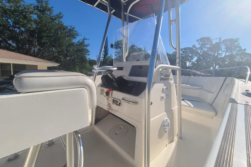 Slide: The Image of 2003 Aquasport 205 Osprey boat interior with seating and console under clear blue sky. - 6
