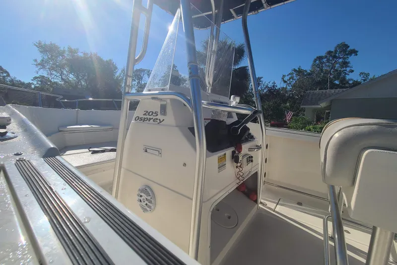 Slide: The Image of 2003 Aquasport 205 Osprey boat interior with console and seating under sunny sky. - 9