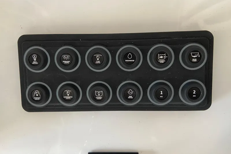 Slide: The Image of Control panel of a 2026 Sportsman Open 232 Center Console boat with labeled buttons. - 16
