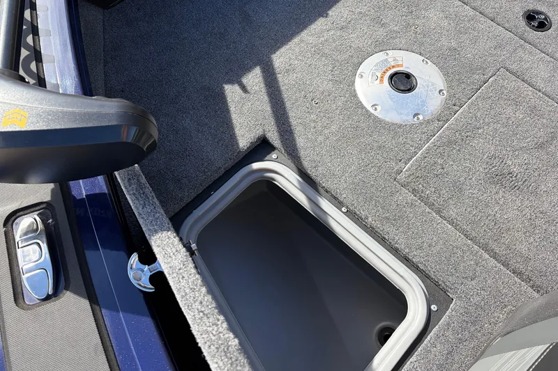 Slide: The Image of 2024 Tracker Targa V-18 Combo boat interior with storage compartment and carpeted floor. - 23