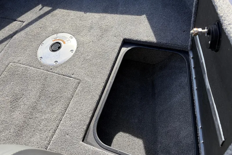 Slide: The Image of 2024 Tracker Targa V-18 Combo boat interior with storage compartment and carpeted flooring. - 24