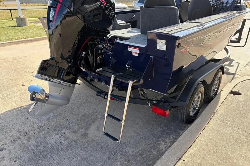 Slide: The Image of 2024 Tracker Targa V-18 Combo boat with outboard motor and trailer, parked on concrete. - 8