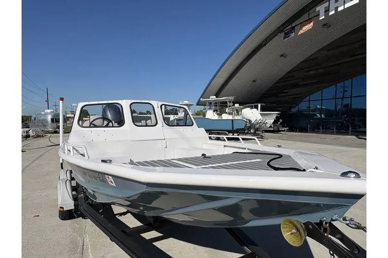 Slide: The Image of 1997 Scully's 18 WT boat on trailer outside a modern building under clear blue sky. - 2